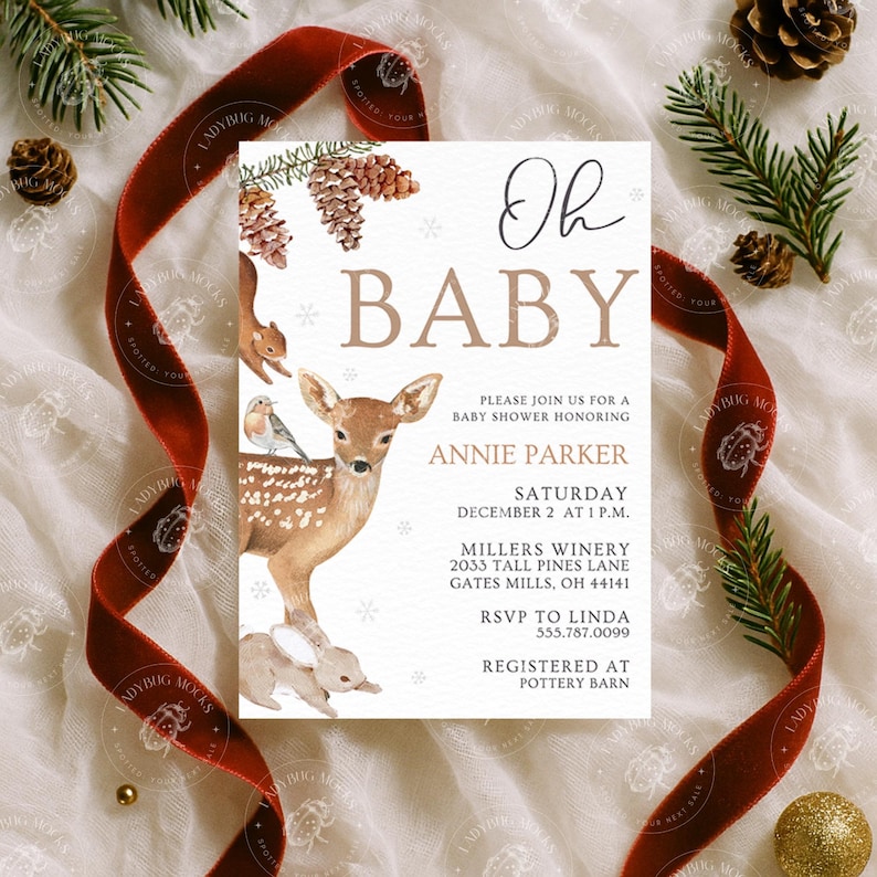 May include: A baby shower invitation with the words "Oh Baby" in elegant script. The invitation features watercolor illustrations of a deer, squirrel, and bunny, with pine cones and snowflakes. A red ribbon and pine branches frame the invitation.