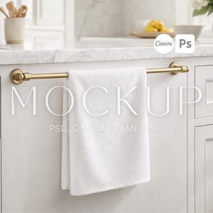 May include: A white waffle-weave towel hangs from a gold-toned towel bar in a kitchen setting. The towel bar is mounted on a white cabinet. The word "MOCKUP" is displayed across the towel, with "PSD, CANVA FRAME, PNG" below it.