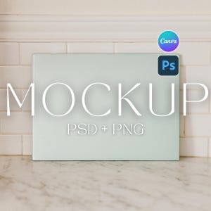 May include: A rectangular, pale green mockup with the word "MOCKUP" in large white letters. Below the word are the words "PSD + PNG". The Canva and Photoshop logos are in the upper right corner. The mockup is on a white and grey surface.