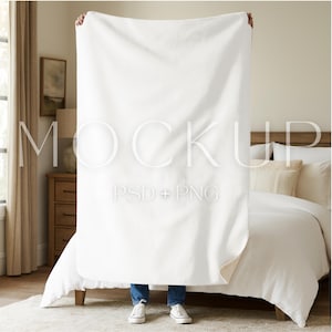 May include: A large, white blanket is held up in front of a bed. The blanket is thick and appears soft. The text "MOCKUP PSD + PNG" is overlaid on the blanket. The bed has white bedding and a wooden headboard.