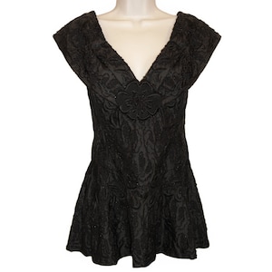 Pode incluir: Um vestido preto sem mangas com decote em V e um design floral. O vestido tem um corpete justo e uma saia rodada.