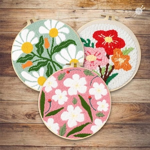 Peut inclure: Trois cerceaux de broderie florale ronds. L'un présente de grandes marguerites blanches avec des centres jaunes sur un fond vert clair. Un autre présente un bouquet de fleurs rouges, roses et oranges. Le troisième a des fleurs blanches sur un fond rose.