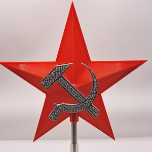 May include: A red five-pointed star with a silver hammer and sickle emblem. The star is mounted on a silver pole. The hammer and sickle are decorated with small, round silver accents.