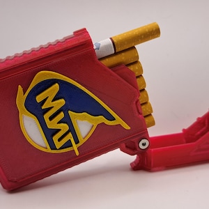 May include: Red cigarette case with a yellow, blue, and white logo. The case is open, revealing several cigarettes. The case is made of a hard material and has a matching red tray.