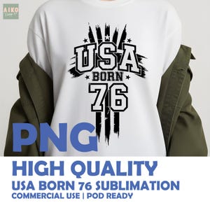 May include: White t-shirt with a black graphic design that reads "USA BORN 76". The design includes the text "USA" in a bold, stylized font, with "BORN" and "76" below. The shirt also has the text "HIGH QUALITY USA BORN 76 SUBLIMATION COMMERCIAL USE | POD READY".