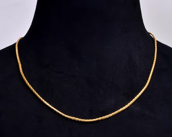 Puede incluir: Un collar de cadena de color dorado con un diseño tejido. El collar se exhibe en un maniquí negro. La cadena es de un color dorado brillante y brillante.