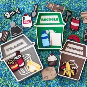 May include: A collection of colorful, cartoon-style recycling and waste items, including a recycle bin, trash can, and compost bin. Other items include a milk carton, cupcake, and a fish skeleton. The items are scattered on a blue and green surface.