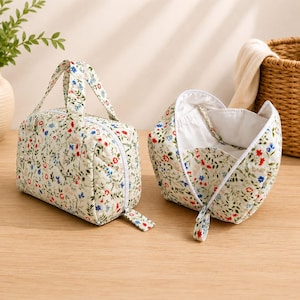 Pu&ograve; includere: Due pochette in tessuto trapuntato con sfondo color crema e un motivo floreale in miniatura nei toni del rosso, blu e verde. Una pochette &egrave; chiusa con manico e cerniera, mentre l'altra &egrave; aperta, rivelando una fodera interna bianca liscia.