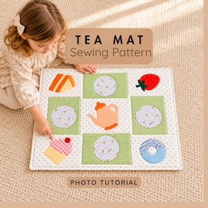 May include: A rectangular tea mat sewing pattern featuring a white fabric with small black dots, green striped rectangular patches, and circular floral fabric appliqués. The mat displays fabric shapes of a teapot, cake, strawberry, cupcake, and donut. Text reads TEA MAT Sewing Pattern and PHOTO TUTORIAL.