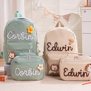 Può includere: Un set di quattro zaini e borse termiche in velluto a coste verde salvia e beige. Le borse sono personalizzate con nomi in corsivo bianco e marrone e decorate con applicazioni floreali e animali. Il nome "Corbin" compare sulle borse verdi e "Edwin" su quelle beige.