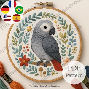 May include: Embroidered hoop art depicting a grey parrot on a branch, encircled by floral and leaf patterns in green, blue, orange, and yellow. The text "PDF Pattern" is visible. The website ThreadsandhoopsShop.Etsy.com is also visible.