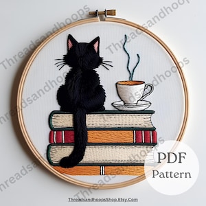 May include: An embroidery hoop featuring a black cat sitting atop a stack of books, with a cup of coffee. The cat is facing away, and the books have orange and red spines. The text "PDF Pattern" is visible.