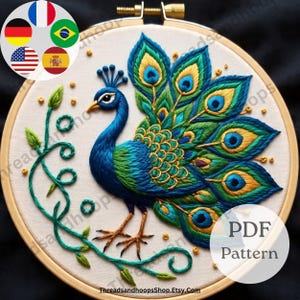 May include: An embroidered peacock design in a wooden hoop. The peacock is rendered in blue, green, and gold thread, with a detailed tail and body. The design includes a leafy vine and the text "PDF Pattern".