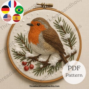 Puede incluir: Bordado de un petirrojo en un aro de madera. El pájaro tiene el pecho naranja, alas marrones y está posado en una rama con agujas de pino verdes y bayas rojas. El bordado está sobre una tela blanca. El texto "PDF Pattern" es visible.