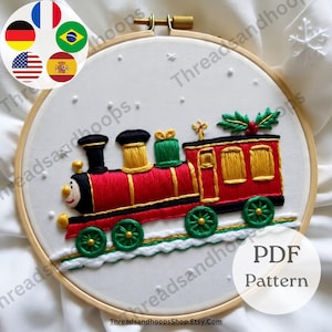 May include: Embroidered Christmas train design in a wooden hoop. The train is red with gold and green accents, green wheels, and a smiling face. The background is white with small white dots. The text "PDF Pattern" is in a white circle.