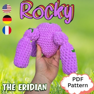 Puede incluir: Un juguete hecho a mano de color lavanda llamado "Rocky" con brazos largos y detalles verdes. La imagen incluye el texto "PDF Pattern" y "The Eridian". El fondo es verde borroso.