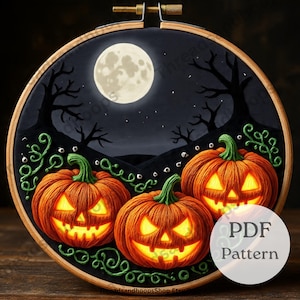 以下が含まれることがあります： 木製のフープに施されたハロウィーンをテーマにした刺繍。満月と裸の木がある夜空を背景に、顔が光る3つのオレンジ色のカボチャが描かれています。緑のつる植物とテキスト「PDF Pattern」も表示されています。