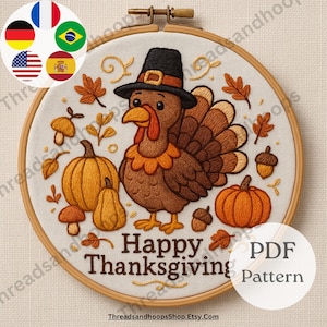 May include: Embroidered Thanksgiving design in a wooden hoop. The artwork features a turkey wearing a pilgrim hat, pumpkins, acorns, and fall leaves. The text "Happy Thanksgiving" is displayed below the turkey. A PDF pattern is also available.