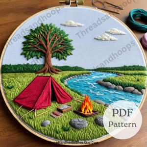 May include: Embroidered camping scene in a wooden hoop. A red tent sits near a river with a campfire, tree, and clouds. The text "PDF Pattern" is visible. The background is light blue.