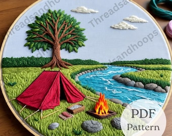 May include: Embroidered camping scene in a wooden hoop. A red tent sits near a river with a campfire, tree, and clouds. The text "PDF Pattern" is visible. The background is light blue.