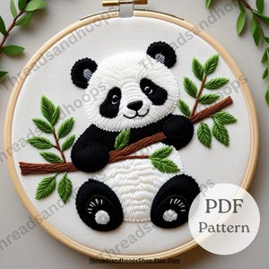 Può includere: Ricamo di un panda nero e bianco che tiene un ramo marrone con foglie verdi, in un cerchio di legno. Il testo "PDF Pattern" è in un cerchio bianco. Artigianato del ricamo.