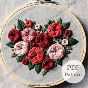 Könnte beinhalten: Ein Stickrahmen mit einem floralen Design aus roten und rosa Rosen und grünen Blättern. Der Text "PDF Pattern" befindet sich in einem weißen Kreis. Der Shop-Name "ThreadsandhoopsShop.Etsy.com" ist sichtbar.