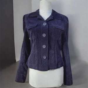 May include: A dark blue corduroy jacket with a collared neckline, four front pockets, and button fastenings. The jacket is displayed on a white mannequin and has long sleeves.