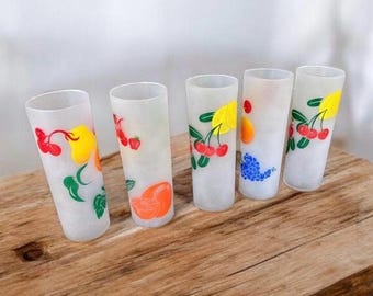 Könnte beinhalten: Satz von fünf gefrosteten Gläsern mit bunten Fruchtmotiven. Die Gläser zeigen Kirschen, Zitronen, Trauben und Orangen.