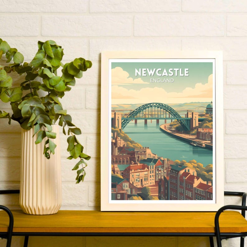 May include: A framed art print featuring a stylized illustration of Newcastle, England. The image showcases the iconic bridge over a river, with buildings and a blue sky. The text "NEWCASTLE ENGLAND" is at the top of the print.