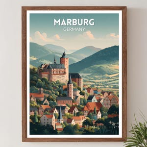 May include: A framed art print of Marburg, Germany, featuring a detailed illustration of a castle and town nestled in a valley. The artwork has a vintage travel poster style, with the text "MARBURG GERMANY" at the top. The color palette includes greens, browns, and blues.