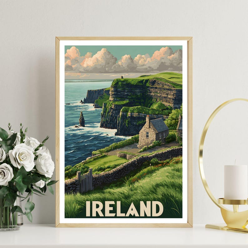 K&ouml;nnte beinhalten: Gerahmter Kunstdruck mit einer malerischen Ansicht der irischen K&uuml;ste. Das Kunstwerk zeigt gr&uuml;ne Klippen, ein Steinh&auml;uschen und das Wort "IRELAND" am unteren Rand. Der Himmel ist mit flauschigen Wolken gef&uuml;llt, und das Meer ist tiefblau.