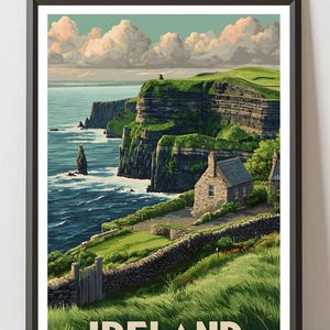 K&ouml;nnte beinhalten: Gerahmter Druck der irischen K&uuml;ste mit den Cliffs of Moher. Das Kunstwerk zeigt ein Steinh&auml;uschen, gr&uuml;ne Klippen und das Meer unter einem bew&ouml;lkten Himmel. Das Wort "IRELAND" ist unten aufgedruckt.