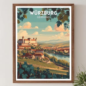 May include: A framed print featuring a scenic view of Würzburg, Germany. The artwork depicts a cityscape with a river, buildings, and rolling hills under a blue sky with clouds. The print includes the text "WÜRZBURG GERMANY".