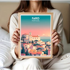 May include: A framed art print featuring a stylized illustration of Faro, Portugal. The artwork depicts a coastal town with white buildings, orange rooftops, and green trees under a sunset sky. The text "FARO PORTUGAL" is at the top.