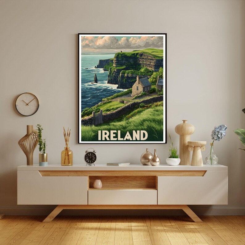 K&ouml;nnte beinhalten: Ein gerahmter Druck der irischen K&uuml;ste mit gr&uuml;nen Klippen, einem Steinh&auml;uschen und dem Wort "IRELAND" in Wei&szlig;. Das Kunstwerk hat eine Vintage-Reiseplakat-&Auml;sthetik und zeigt Meer und Himmel.