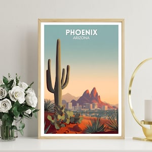 May include: A framed art print featuring a stylized desert landscape with a large saguaro cactus, mountains, and the city skyline. The print has the text "PHOENIX ARIZONA" in white. The color palette includes shades of red, orange, green, and blue.