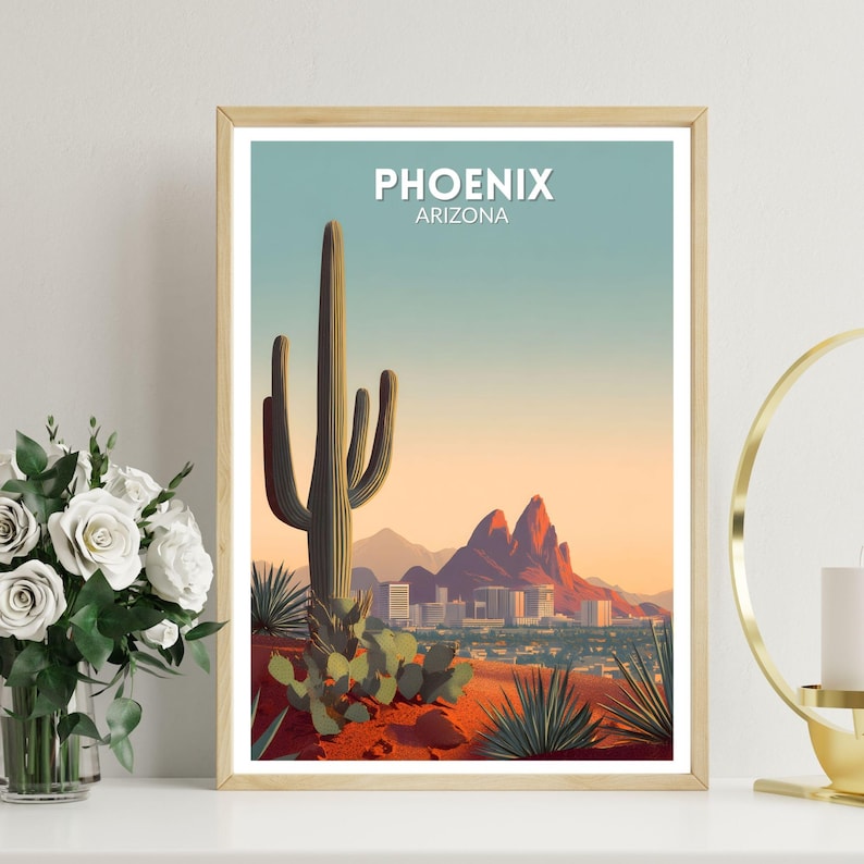 May include: A framed art print featuring a stylized desert landscape with a large saguaro cactus, mountains, and the city skyline. The print has the text "PHOENIX ARIZONA" in white. The color palette includes shades of red, orange, green, and blue.