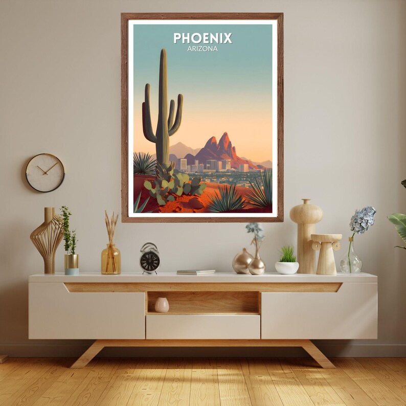 May include: A framed art print featuring a desert landscape with a large saguaro cactus, mountains, and a city skyline. The print has the text "PHOENIX ARIZONA" at the top. The color palette includes shades of green, orange, and blue.