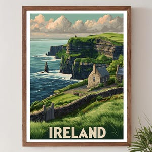 K&ouml;nnte beinhalten: Ein gerahmter Druck mit einer malerischen Ansicht der irischen K&uuml;ste. Das Kunstwerk zeigt gr&uuml;ne Klippen, ein Steinh&auml;uschen und das Wort &bdquo;IRELAND&ldquo; in fetten Buchstaben. Der Himmel ist mit Wolken gef&uuml;llt, und das Meer ist tiefblau.