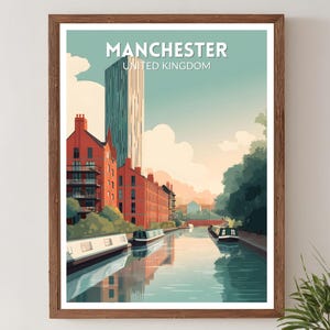 May include: A framed art print featuring a stylized illustration of Manchester, United Kingdom. The print showcases a canal with boats, red brick buildings, and a tall modern skyscraper under a blue sky. The word "MANCHESTER" is at the top.