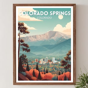 Puede incluir: Una impresión artística enmarcada que presenta un paisaje estilizado de Colorado Springs, Colorado. La obra de arte representa una cordillera, un horizonte urbano y un colorido follaje otoñal. Las palabras "COLORADO SPRINGS" y "COLORADO" están impresas en la parte superior.
