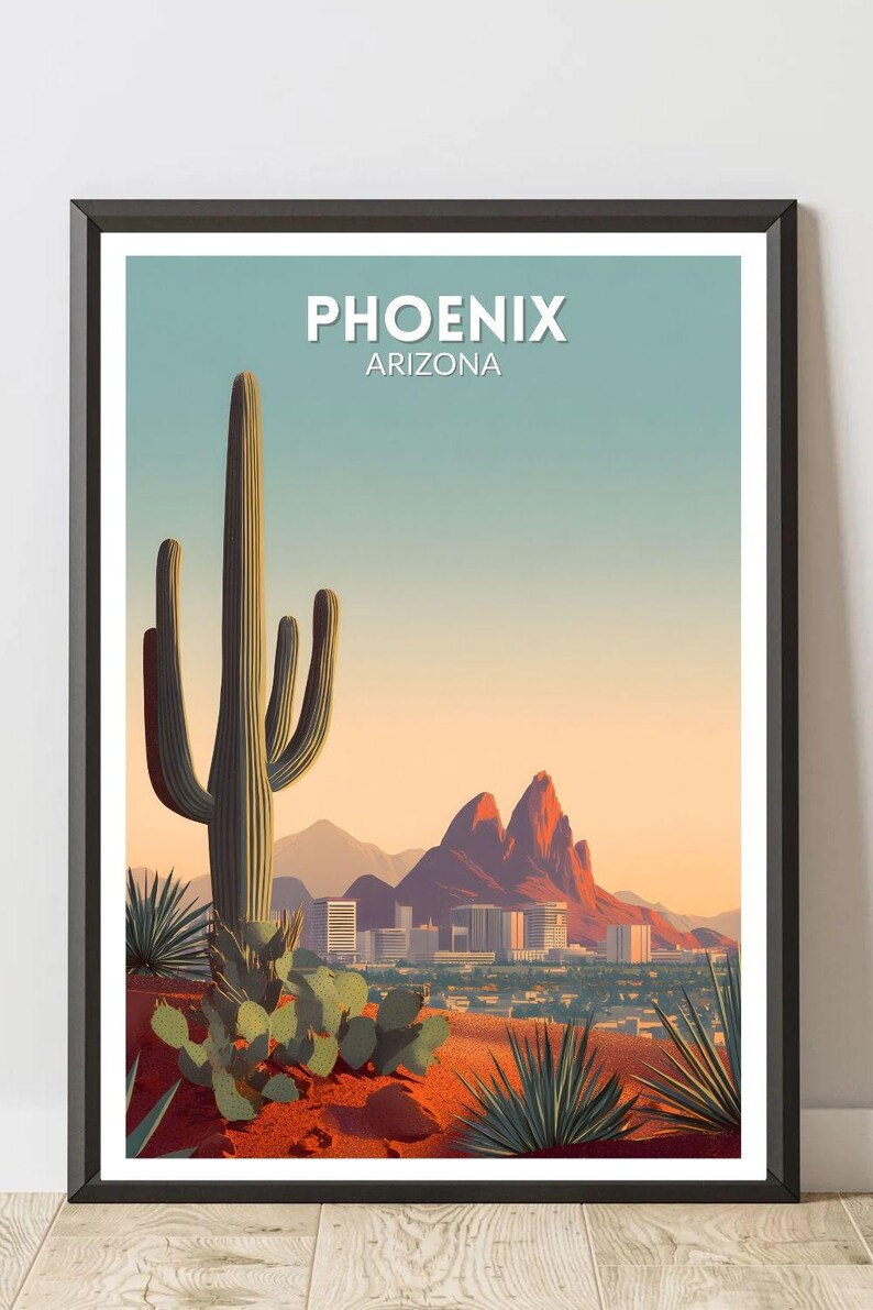 May include: Framed art print featuring a desert landscape with a large saguaro cactus in the foreground. The image includes the text "PHOENIX ARIZONA" at the top, with a city skyline and mountains in the background. The color palette includes shades of green, orange, and blue.