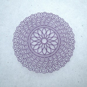 May include: A purple lace doily with a floral design in the center.