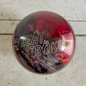 May include: A red, black, and purple bowling ball with a white "HEAT STROKE" graphic with a flame design.