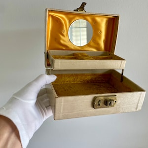 May include: A vintage white jewelry box with a gold interior and a small mirror. The box has a lock and key.