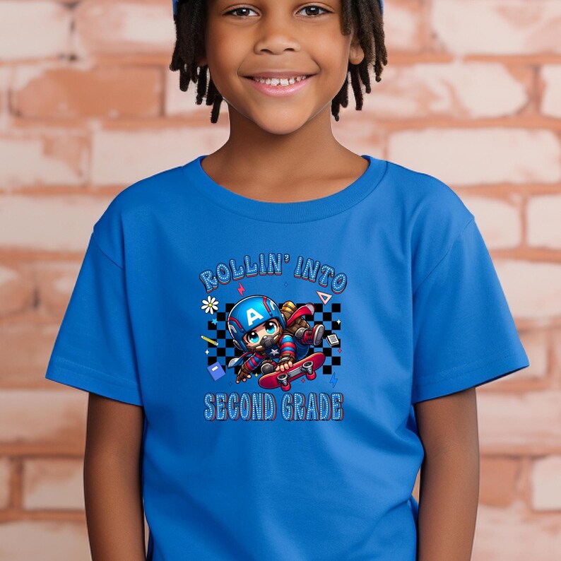 May include: A blue t-shirt featuring a cartoon character riding a skateboard. The character wears a helmet with the letter "A" and is surrounded by a checkered pattern and the words "ROLLIN' INTO SECOND GRADE".