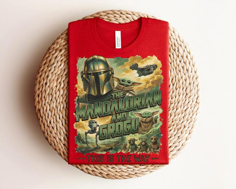 Puede incluir: Una camiseta roja con un estampado gr&aacute;fico de The Mandalorian y Grogu. El dise&ntilde;o incluye el texto "The Mandalorian and Grogu" y "This is the way" junto con ilustraciones de un personaje con casco, peque&ntilde;as criaturas verdes y una nave espacial.