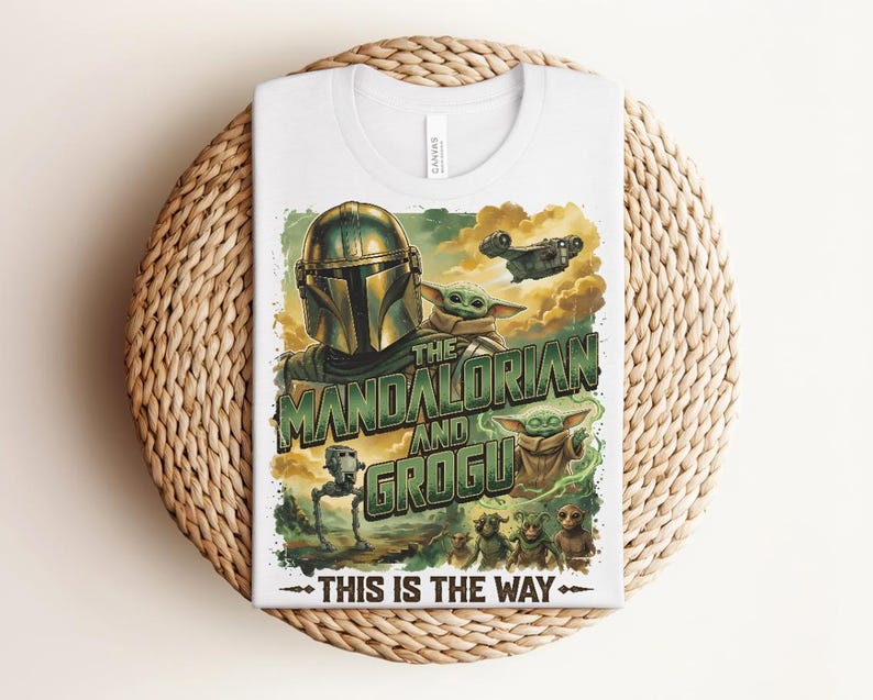 Puede incluir: Una camiseta blanca con un estampado gr&aacute;fico de The Mandalorian y Grogu. El dise&ntilde;o incluye el texto "THE MANDALORIAN AND GROGU" y "THIS IS THE WAY" junto con ilustraciones de un personaje con casco, peque&ntilde;as criaturas verdes y una nave espacial.