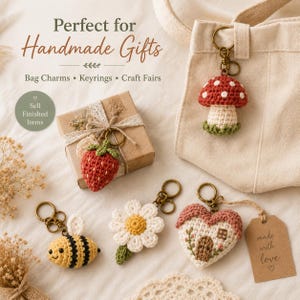 May include: Crochet keychains featuring a red and white mushroom, a red strawberry, a yellow and black bee, a white daisy with a yellow center, and a heart-shaped house with a brown door, all attached to bronze-colored metal rings.