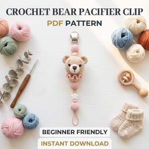 Pode incluir: Um prendedor de chupeta de urso de crochê com uma cabeça de urso marrom claro, detalhes em rosa e um clipe de metal. A imagem também mostra novelos de lã, uma agulha de crochê, uma chocalho de madeira e meias de bebê. O texto na imagem diz "CROCHET BEAR PACIFIER CLIP PDF PATTERN".
